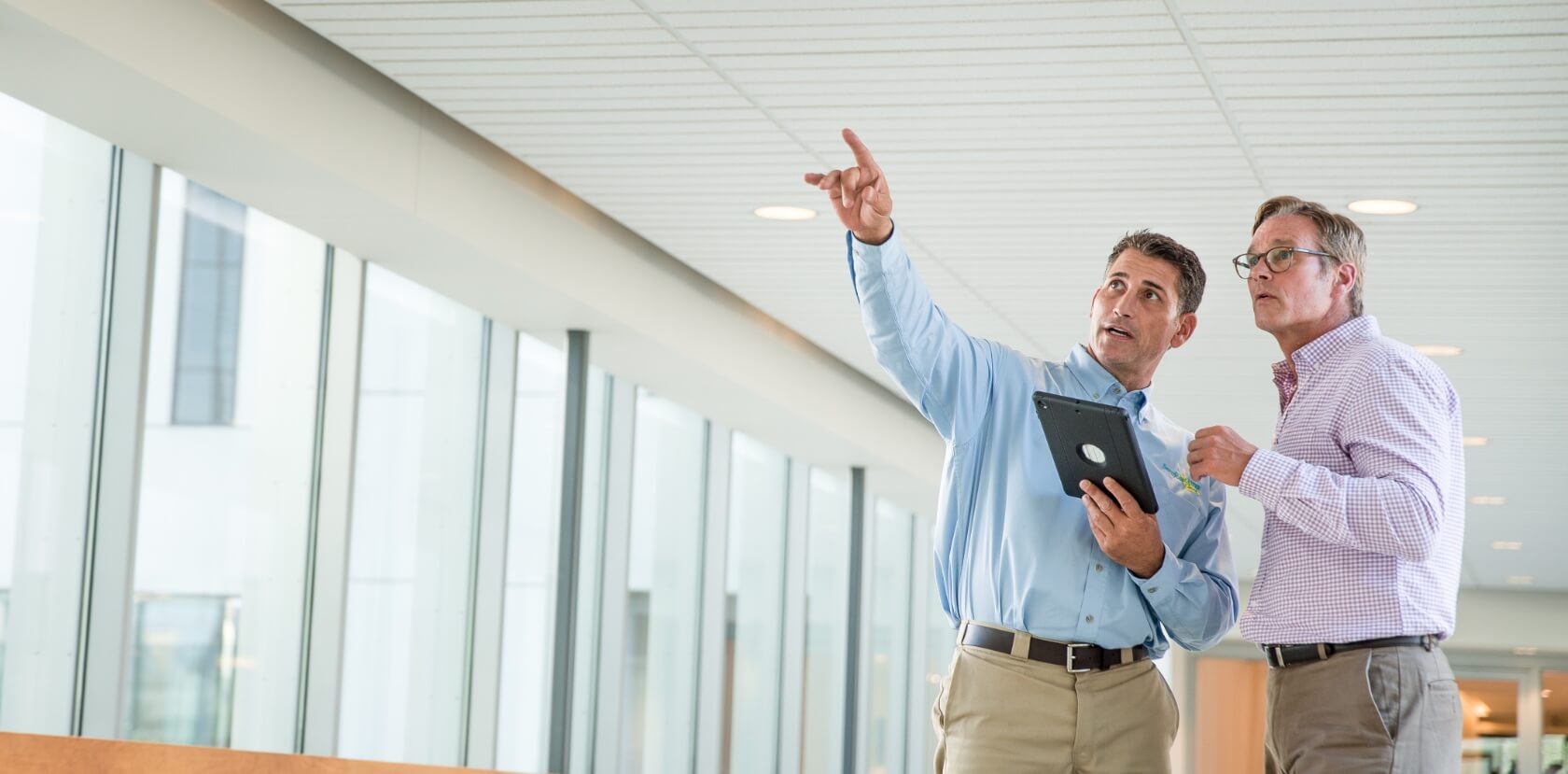A servicemaster consultant pointing to something off camera with a customer looking in the same direction to where he's pointing